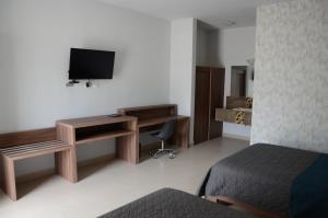 um quarto de hotel com uma cama, uma secretária e uma televisão em HOTEL MONARCA em Ciudad Victoria