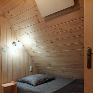 a bed in a room with a wooden wall at Domek Pod Tylką in Grywałd