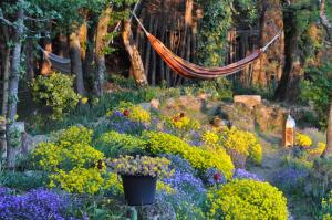 a hammock in a garden with flowers and trees at Chambre d'hôtes de Thorée in Maclas