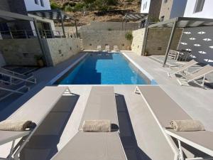 a swimming pool with two lounges and a swimming pool at Matala Prime Villas in Matala