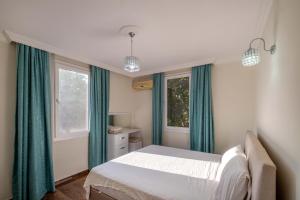 een slaapkamer met groene gordijnen, een bed en een raam bij Kayaköy İncir villa özel yüzme havuzlu in Fethiye