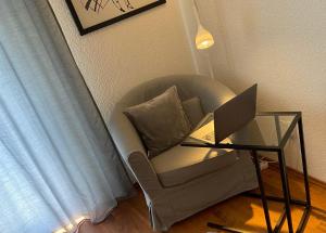 a living room with a chair and a laptop on a glass table at NordiCasa in Eger