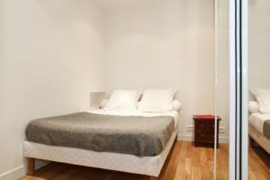 ein weißes Schlafzimmer mit einem Bett und einem Spiegel in der Unterkunft JULES JO in Paris