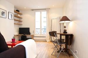 ein Wohnzimmer mit einem Sofa, einem Tisch und einem TV in der Unterkunft JULES JO in Paris