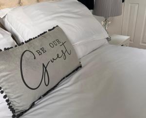 a bed with a pillow with the words be our guest at Cathedral Apartment in Lichfield