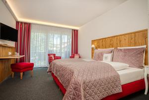 um quarto de hotel com uma cama grande e uma cadeira vermelha em Landhaus Sommerau em Buchenberg