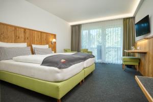 a hotel room with a large bed and a television at Landhaus Sommerau in Buchenberg