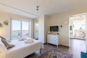 een witte slaapkamer met een bed en een televisie bij Penthouse with a panoramic rooftop in Trastevere with seasonally Jacuzzi in Rome