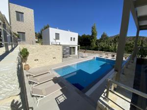 a swimming pool with lounge chairs and a house at Matala Prime Villas in Matala