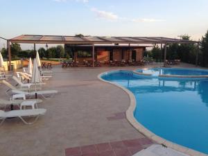 a swimming pool with lounge chairs and a pavilion at Achillio Hotel in Komotini