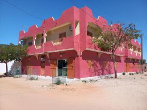 un bâtiment rose au milieu du désert dans l'établissement SAM RESIDENCE Jàmm ak Cofeel, à Saint-Louis