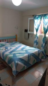 een slaapkamer met een bed met een dekbed en een raam bij H2Otel in Salta