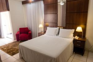 a bedroom with a large bed and a red chair at Ibituruna Center Hotel in Governador Valadares +139 photos