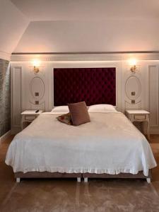 a bedroom with a large white bed with a red headboard at Cardinale Resort in Iaşi