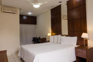 a hotel room with a white bed and a desk at Ibituruna Center Hotel in Governador Valadares