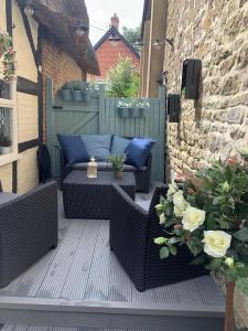 a patio with wicker chairs and a couch and flowers at Chapel Cottage in Pewsey