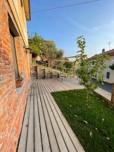 una terraza de madera junto a un edificio de ladrillo con un árbol en Le camere del Tiglio, en Treiso