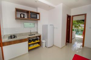 a white kitchen with a refrigerator and a microwave at Apart-Hotel Bella Vida Suítes e Apartamentos in Morro de São Paulo