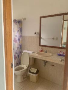 een badkamer met een toilet, een wastafel en een spiegel bij Sunset Bay Colan in Colán