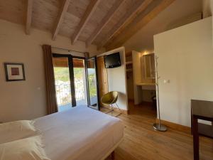 a bedroom with a bed and a desk and a television at La Baranda in Chulilla