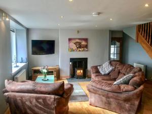 a living room with two leather couches and a fireplace at West Cottage Todrig Farm in Greenlaw