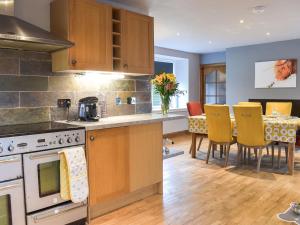 a kitchen with wooden cabinets and a table with yellow chairs at West Cottage Todrig Farm in Greenlaw