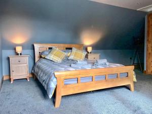 a bedroom with a wooden bed and two night stands at West Cottage Todrig Farm in Greenlaw