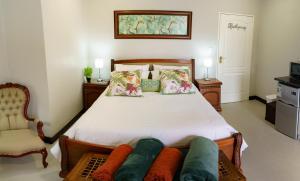 a bedroom with a large bed and a chair at Mi Vida Guesthouse in Klerksdorp