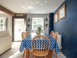 a blue dining room with a table and chairs at The Barn House in Ugborough