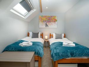 two twin beds in a room with a painting on the wall at The Barn House in Ugborough