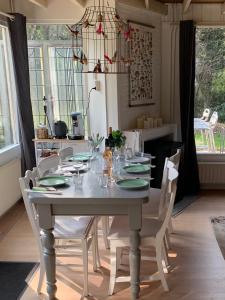 uma mesa de jantar com cadeiras brancas e uma mesa branca com placas verdes em Het Slakkenhuisje em Maarn