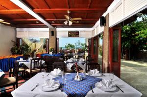 a restaurant with tables and chairs and a ceiling at Karon Princess Hotel SHA EXTRA Plus in Karon Beach