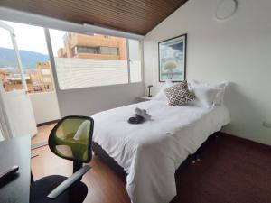 a bedroom with a bed and a chair and a window at HABITACION 8 AMPLIA baño y balcón privado UNICENTRO in Bogotá