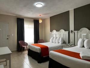 een hotelkamer met twee bedden en een tafel en stoelen bij HOTEL LOS ROBLES in Nuevo Laredo