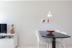 ein Esszimmer mit einem schwarzen Tisch und weißen Stühlen in der Unterkunft Praia Residence in Porto De Galinhas