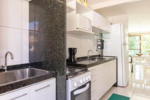 a white kitchen with a sink and a stove at Praia Residence in Porto De Galinhas