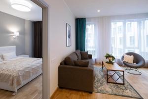 a bedroom with a bed and a couch and a chair at Riverside Design Apartment with underground private parking in Rīga