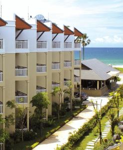 an apartment building with the ocean in the background at Karon Princess Hotel SHA EXTRA Plus in Karon Beach