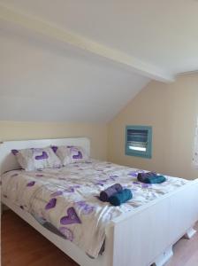 ein Schlafzimmer mit einem großen weißen Bett mit lila Kissen in der Unterkunft Resetovac in Batočina
