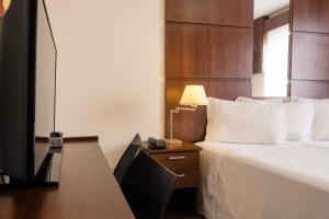 a hotel room with a bed and a desk with a television at Ibituruna Center Hotel in Governador Valadares