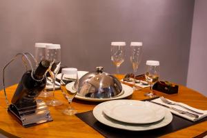 a wooden table with plates and wine glasses on it at Bangalô Motel by Drops in Santa Maria
