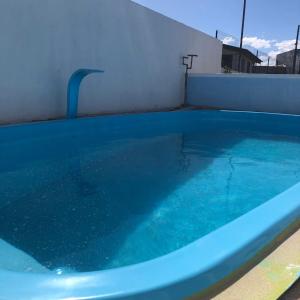 a large blue swimming pool next to a white wall at Pousada Patriarca Silva in Rio Grande
