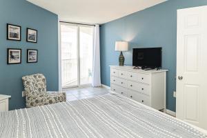 1 dormitorio con 1 cama, 1 silla y TV en New River Retreat, en North Topsail Beach