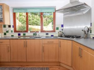 cocina con armarios de madera, fregadero y ventana en Taw River View, en Okehampton