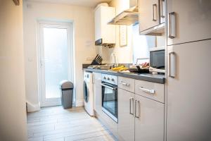 cocina con fregadero y fogones horno superior en Spacious 1-Bedroom Home with free private parking en Swansea