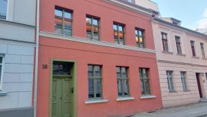 a red building with a green door on a street at Apartamenty K&B Toruń in Toruń