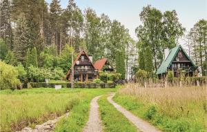 uma casa na floresta com uma estrada de terra em frente em Pet Friendly Home In Barczewo With Kitchenette em Barczewo