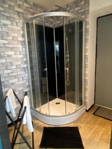 a glass shower in a room with a brick wall at Chambre avec spa privatif in Amiens