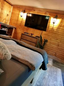 a bedroom with a flat screen tv on a wooden wall at Tölgyes Menedék 2. in Noszvaj