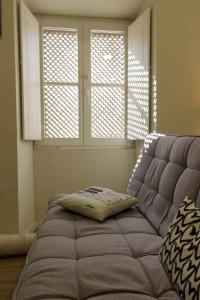 um sofá sentado numa sala com duas janelas em Apartamento Almirante T1 by YHA em Tavira